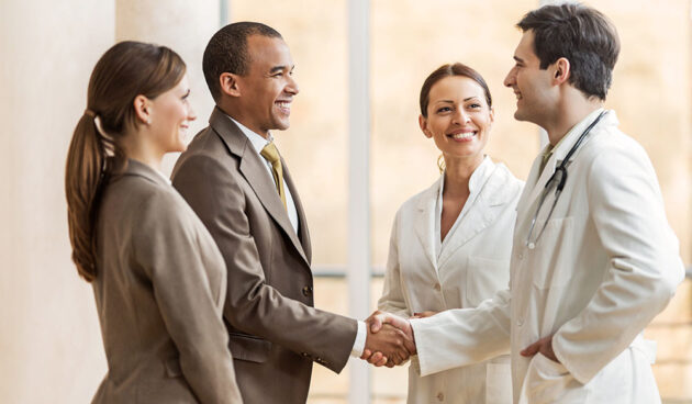 Business people collaborating with doctors. African American businessman shaking hands with a male doctor.