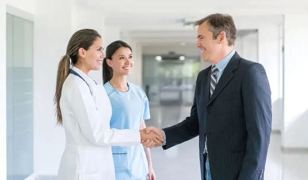 Doctor greeting health insurance agent with a handshake at the hospital