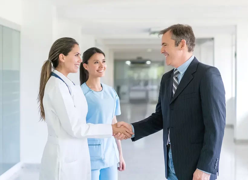 Doctor greeting health insurance agent with a handshake at the hospital