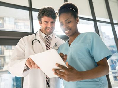 Nurse and doctor looking at the information of a patient on a digital tablet both looking very happy and smiling